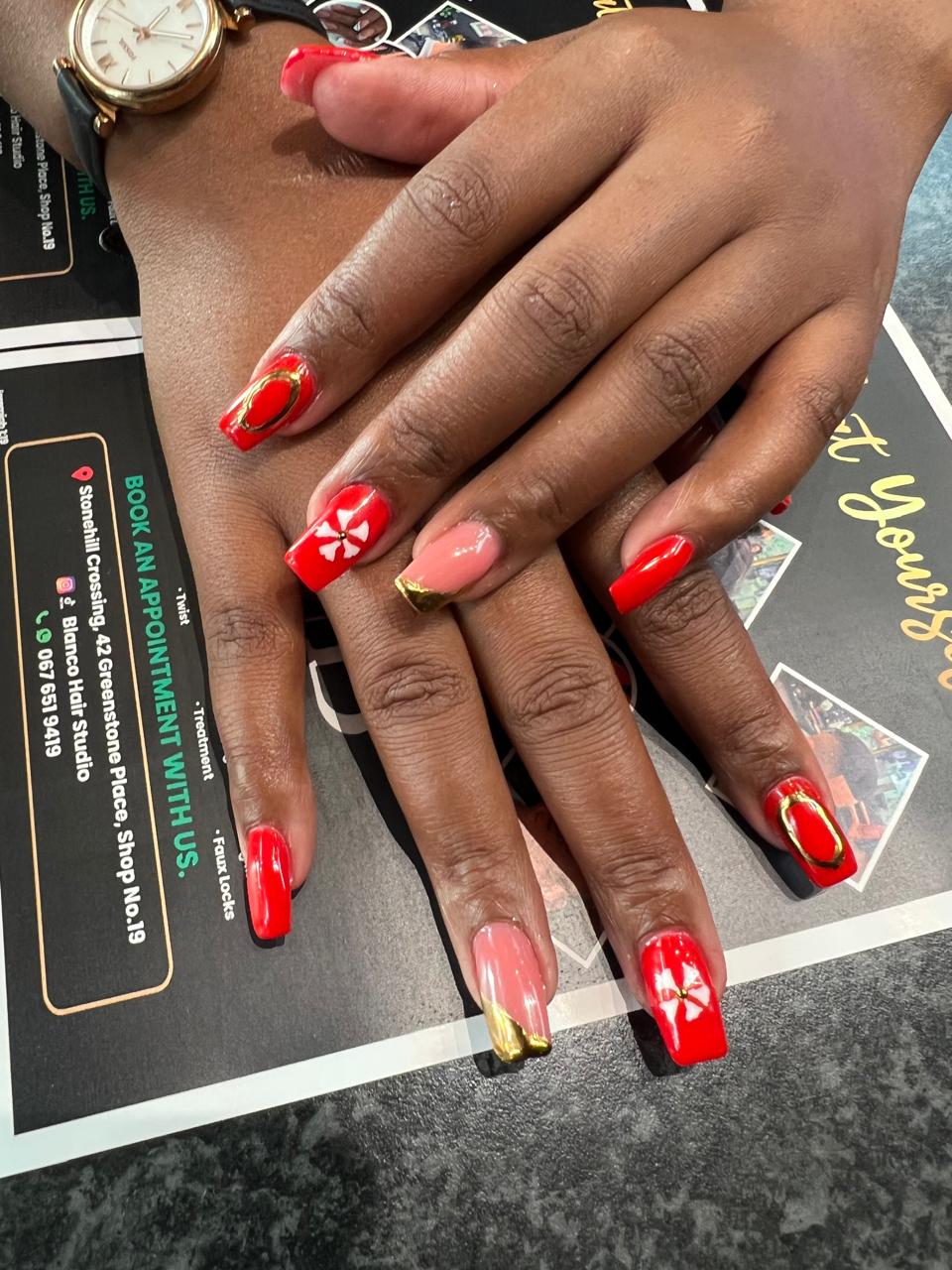Red nail art with gold foil accents